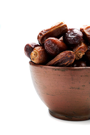 Dried dates fruit for iftar on Ramadan in the bowl isolated over a white backgroundの写真素材