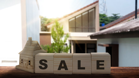The row of wooden cubes with sale text and a wooden house on the table with a real estate background. Real estate sales conceptの写真素材