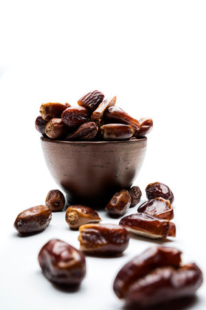 Dried dates fruit for iftar on Ramadan in the bowl isolated over a white background
