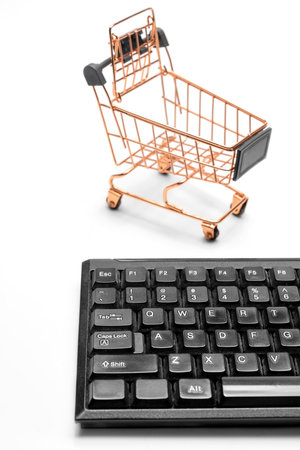 Model figure of shopping cart and computer keyboard isolated over white bckground. Black Friday and Cyber Monday concept. Business retail shop store marketing online. Shipping service technology and order check outの写真素材