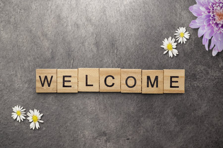 A row of wooden cubes with welcome text with a black background. Introduction concept