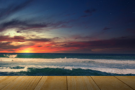 Wooden table with a view of the blue ocean and sunset scene background. Nature background