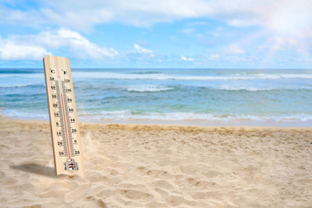 Thermometer with hot temperature on the beach. Environment, global warming, and climate change conceptの写真素材