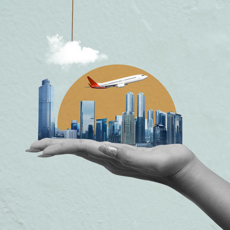 A hand holding a model airplane in front of a cityscape. Concept of adventure and excitement, as if the person is about to embark on a journeyの写真素材