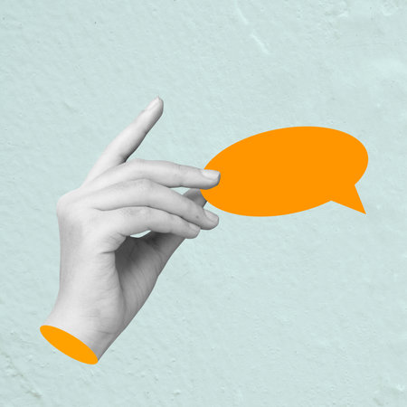 Black and white hand gently holds an empty orange speech bubble against a textured blue background, perfect for various uses like marketing and social mediaの写真素材