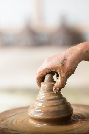 Human hand sculpting a craft from raw clay on the pottery wheelの写真素材
