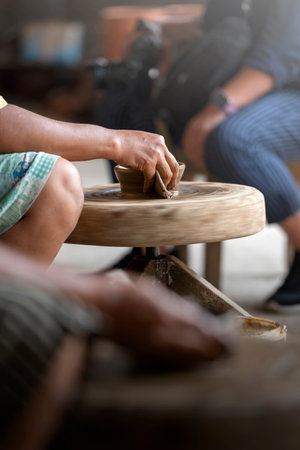 Human hand sculpting a craft from raw clay on the pottery wheel