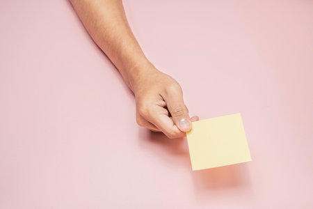 A human hand holding a note with a colored background