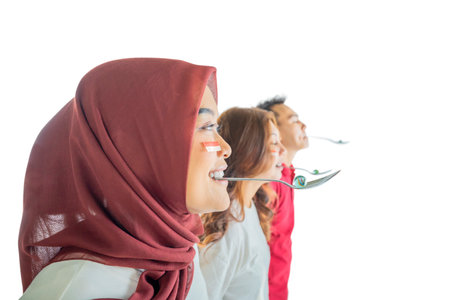 Three people with spoons are marble racing, one of them is wearing a red scarf. Scene is lighthearted and fun, as the people are enjoying an activity togetherの写真素材