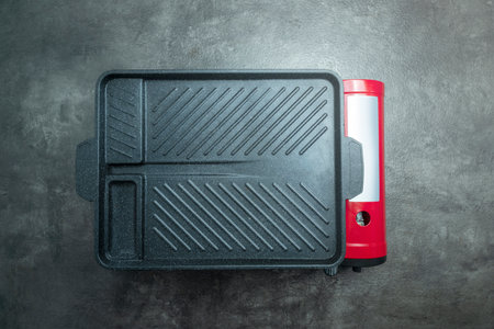 A red and black pan sits on a grey surfaceの写真素材