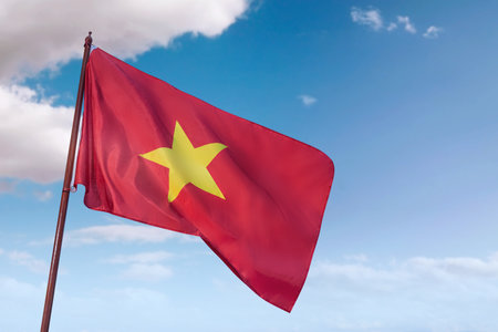 A red and yellow flag with a yellow star on it is flying in the sky. The flag is from Vietnam and is waving in the wind. The sky is clear and blue, with a few clouds scattered throughoutの写真素材