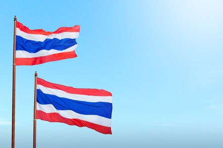 A red, white, and blue Thailand flag is flying in the sky