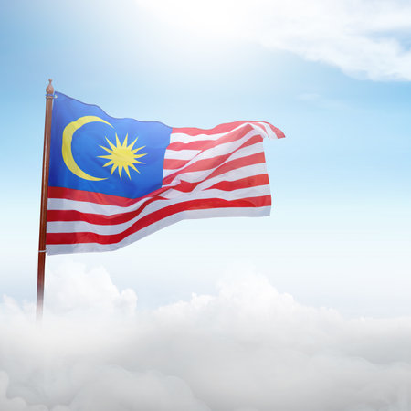 A Malaysia flag with a red stripe and a blue stripe with a yellow star in the middle. The flag is flying in the skyの写真素材