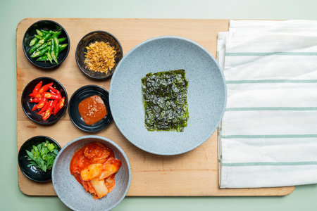 A wooden cutting board with a variety of bowls of food on it. The bowls are filled with different types of food, including a bowl of greens. Concept of abundance and varietyの写真素材