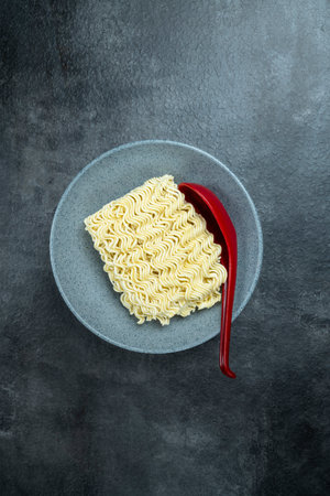 A bowl of instant noodles with a red spoon on topの写真素材