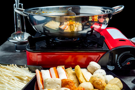 A red and silver pot with food in it sits on a stove. The pot is filled with a variety of food,...
