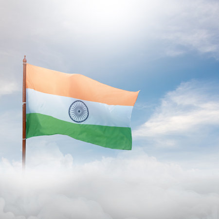 A Indian flag with the colors green, white and red. The flag is waving in the wind. The sky is...