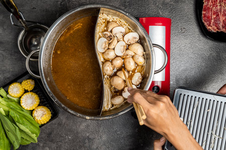 A person is cooking a dish with two bowls of food, one of which is filled with mushrooms