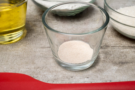 A glass bowl with a yeast in it sits on a table next to other bowls and a bottleの写真素材