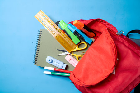 A red backpack with a ruler, scissors, and other school supplies. The backpack is open, revealing the contents inside. Concept of organization and preparedness for schoolの写真素材