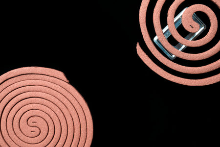 A mosquito coils is on a black background. The spiral is brown and has a shiny surfaceの写真素材
