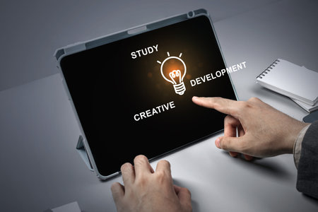 A person is pointing at a tablet with the words study, creative, development. Learning conceptの写真素材