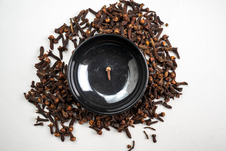 A bowl of cloves is on a table with a pile of cloves on top of itの写真素材