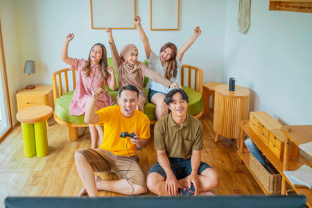 An Indonesian group of people are playing video games in a living room. The scene is fun and lightheartedの写真素材