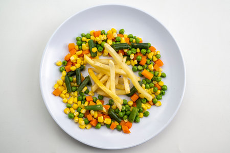 A plate of food with a variety of vegetables and a few french friesの写真素材