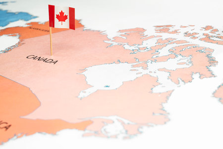 A map of Canada with a Canadian flag on it. The flag with maple leaf and red and white color. Travel and government conceptの写真素材