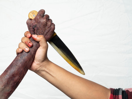 A zombie hand with a bloody wound fighting with a man isolated over a white background. A zombie...