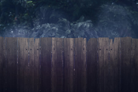 Wooden fence surrounded by leaves on the background on the night. Dramatic smoke or fog effect. Mockup. Copy Space. Wallpaper or Halloween backgroundの写真素材