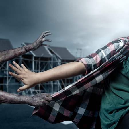 A zombie hand with a bloody wound grabs a human shirt with midnight background. Scene has dark and scary. Zombie, devil, evil, satan, or monster hands. Spooky Halloween conceptの写真素材