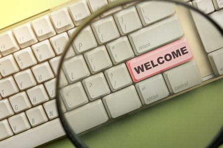 Word "Welcome" written on keyboard button looked through the magnifying glass. Welcome greeting for invitation, express hospitality, greet, show acceptance. Design for business or marketing conceptの写真素材