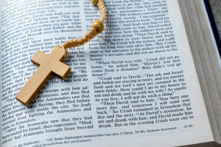 Wooden religion cross on rosary beads and opened blue book of Holy Bible. It is laying on a wooden...