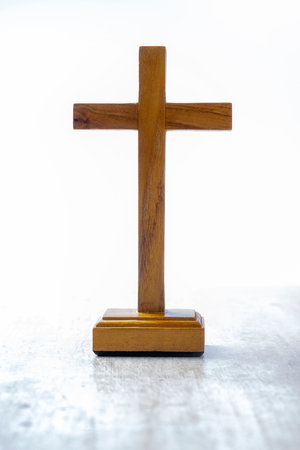 Wooden religion cross standing on bright background. Religious christian holiday. Symbol of faith in...