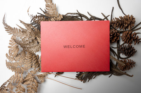 Top view of red envelope and postcard with words Welcome and brown leaves on it. Welcome greeting for invitation, greet, show acceptance. Design for business or marketing conceptの写真素材