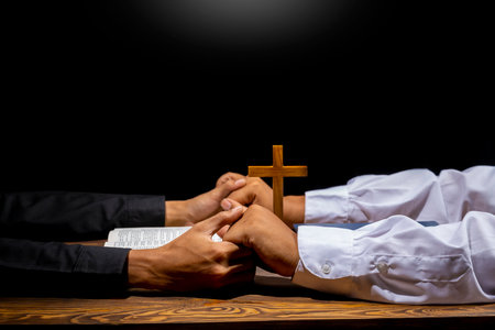 Man praying together with religion cross and on a opened holy bible. Symbol of faith and worship in...