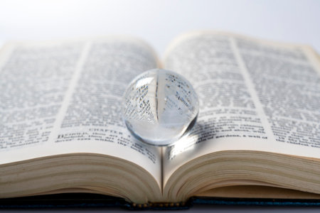 Opened book of Holy Bible with glass ball. It is laying on white background. Symbol of faith and worship in God. Religious christian service, missionary, holiday or conceptの写真素材