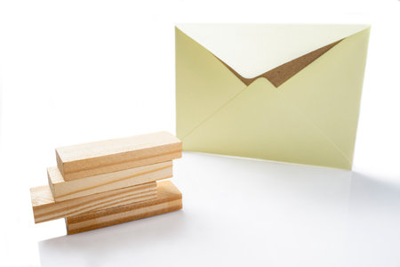 Envelope and postcard with stack of wooden blocks on white background. Mockup, blank template, copy space. Greeting or invitation card with flat lay styleの写真素材
