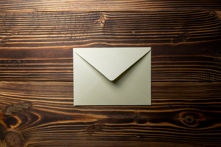 Top view of envelope and postcard on wooden background. Mockup, blank template, copy space. Greeting or invitation card with flat lay styleの写真素材