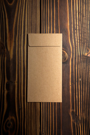Top view of brown envelope and postcard on wooden background. Mockup, blank template, copy space....