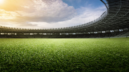 Empty football stadium with green field and blue sky. The field is ready for a game. Concept of Professional sport, Competition, Championship and match. Soccer stadium field backgroundの写真素材