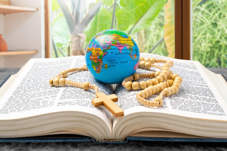 Opened book of Holy Bible with rosary beads and globe. Symbol of faith and worship in God. Religious christian service, missionary, holiday or conceptの写真素材