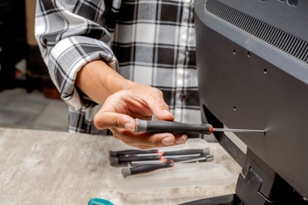Man technician repairing television with a screwdriver. Service, maintenance or repairing conceptの写真素材