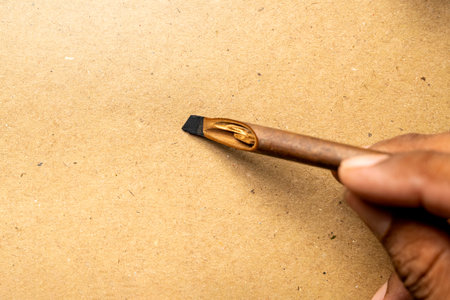 Human hand writing using calligraphy reeds on brown card. Mockup. Copy space. Reeds pen ink for...