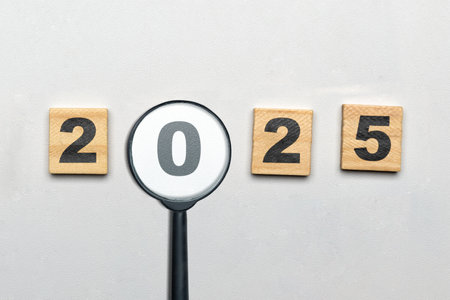 Top view of 2025 number written on wooden cubes look through magnifying glass. Happy New Year concept or celebrationの写真素材