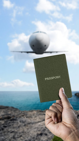 Human hand holding a passport with flying commercial airplane in the sky background. Travel by airplane conceptの写真素材