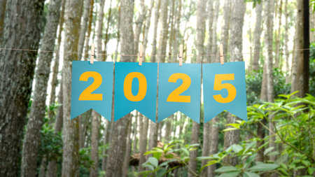 Text of Happy New Year 2025 written on hanging paper with trees background. Happy New Year concept or Celebrationの写真素材