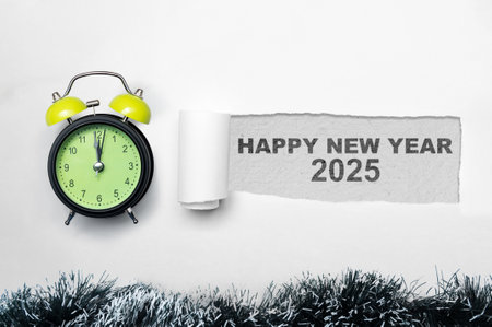 Top view of alarm clock and ripped paper with the text of Happy New Year 2025 written on a white...